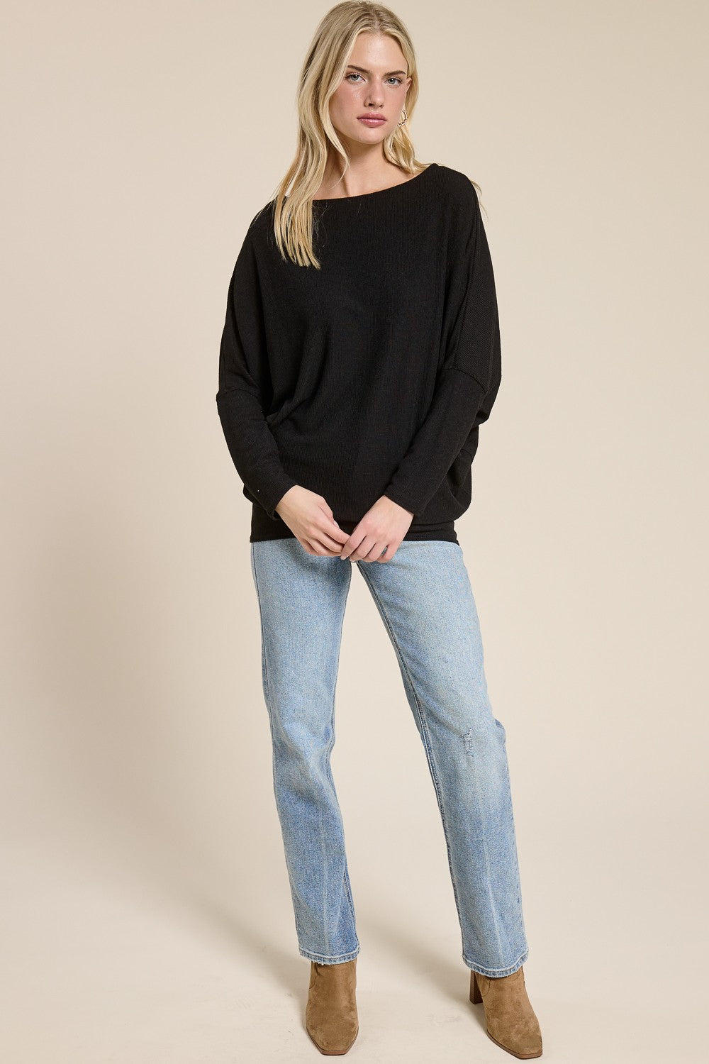 woman wearing a black oversized sweater with relaxed sleeves and light blue straight leg jeans