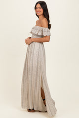 woman wearing a light beige off-the-shoulder maxi dress with a ruffled top and side slit