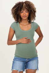 woman wearing a green ribbed short sleeve maternity top and holding her baby bump