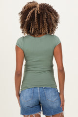 woman wearing a green cap sleeve maternity top with a fitted style and ruched details, paired with denim shorts