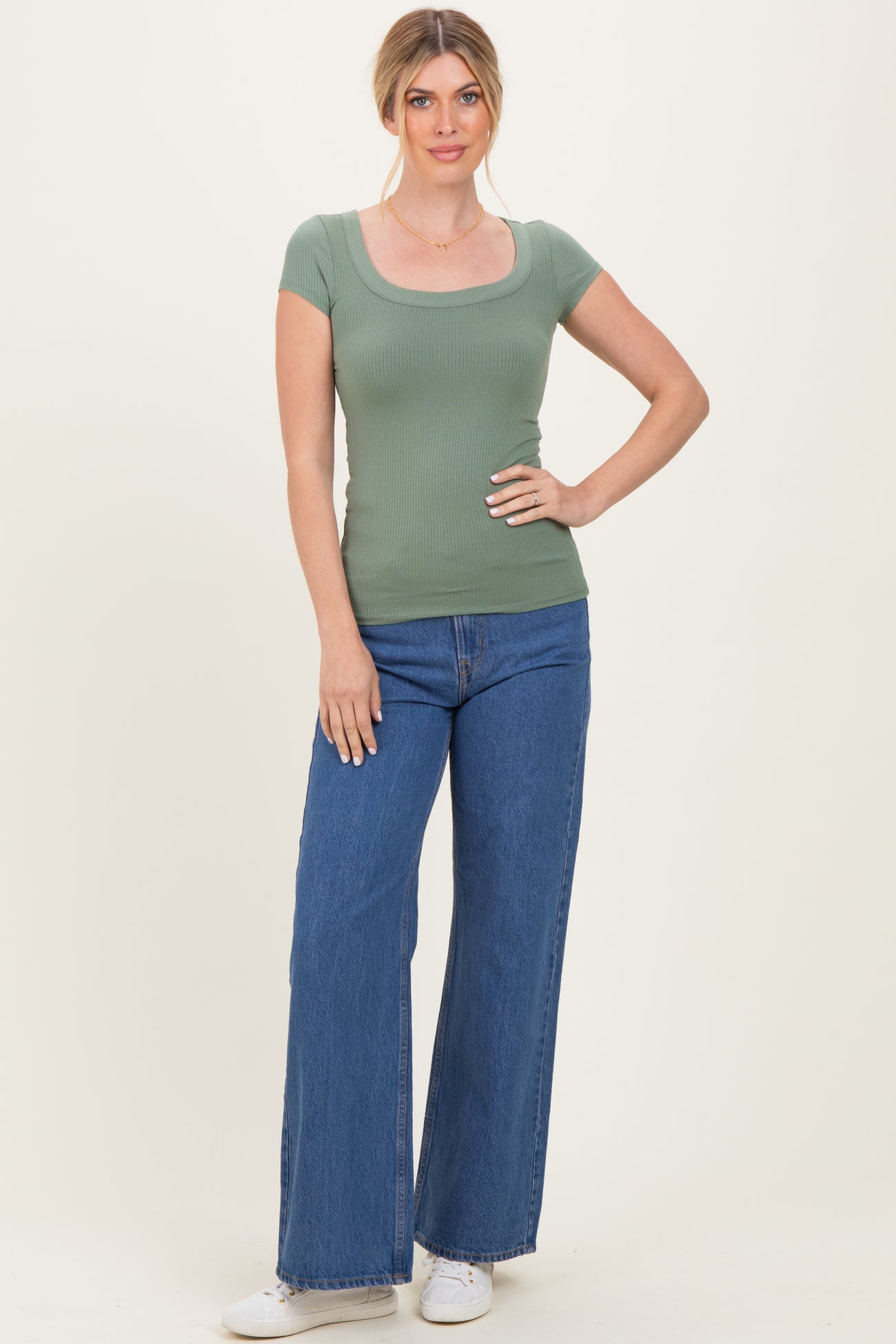 woman wearing a fitted green ribbed short sleeve top and high-waisted wide-leg jeans