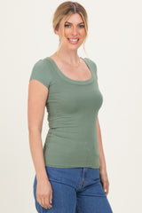woman wearing a green ribbed short sleeve top and blue high-waisted jeans