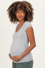 woman wearing a gray short sleeve maternity top and holding her baby bump