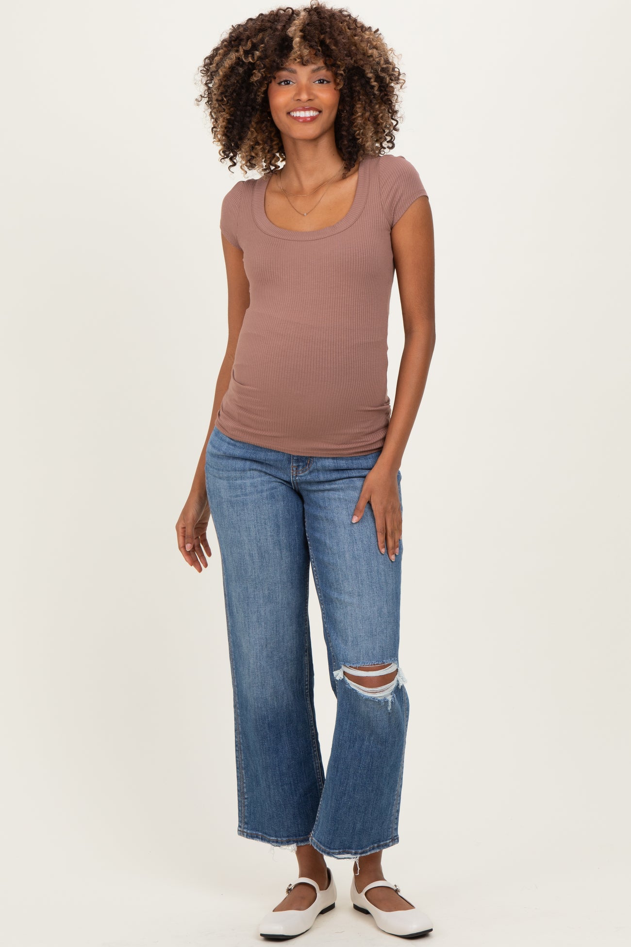 woman wearing a brown ribbed maternity top and distressed wide-leg jeans, showing off her baby bump