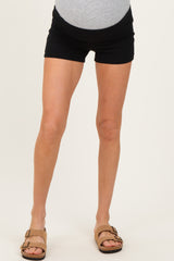 woman wearing black maternity shorts, showcasing her baby bump, paired with brown sandals