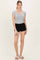 woman wearing a gray fitted short sleeve top and black shorts, standing with a neutral background