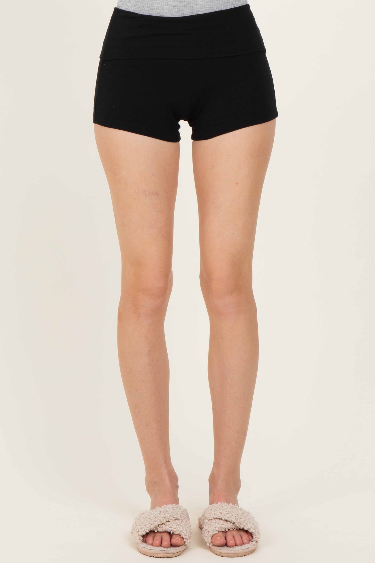woman wearing black high-waisted shorts with a fitted style and soft texture, paired with fuzzy slippers