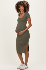 woman wearing a dark olive green ribbed maternity dress with short sleeves and a side slit, showcasing her baby bump