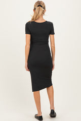 woman wearing a black short sleeve maternity dress with a fitted silhouette and side slit