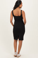 woman wearing a black ribbed maternity dress with a rear slit, showing her back and sandals