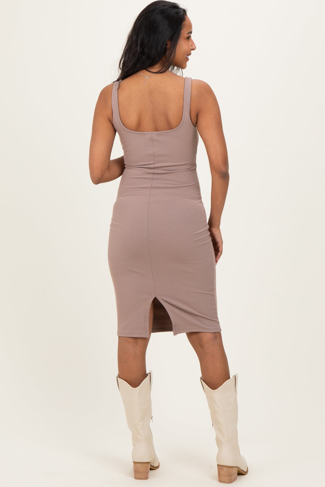 woman wearing a taupe ribbed maternity dress with a slit at the back and white cowboy boots