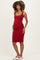 woman wearing a fitted red ribbed maternity dress with a square neckline and holding her baby bump
