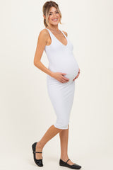 woman wearing a white bodycon maternity dress and holding her baby bump