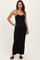 woman wearing a black spaghetti strap maternity maxi dress with button details and showing her baby bump