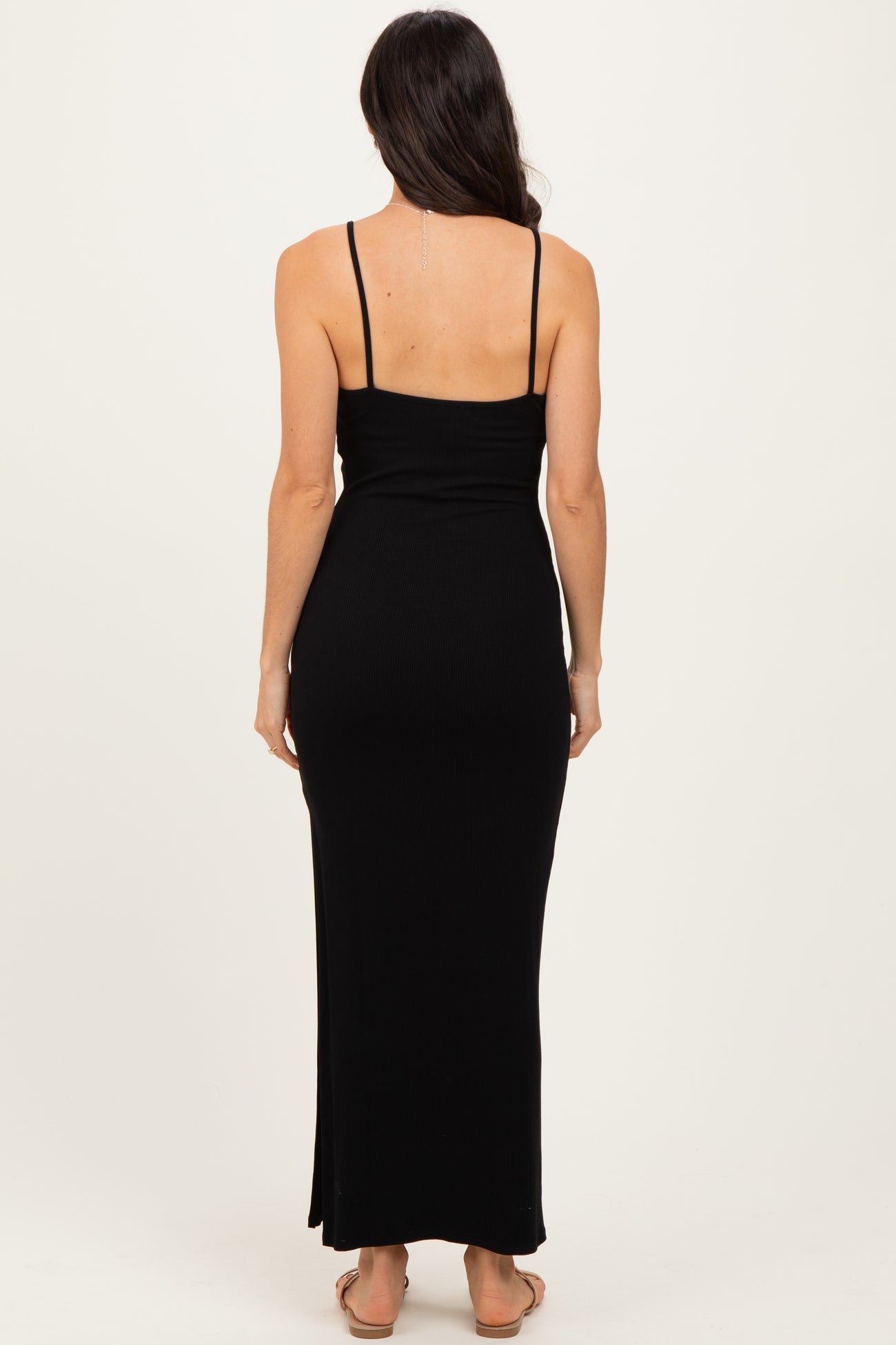 woman wearing a black ribbed maxi dress with spaghetti straps, showing the back view