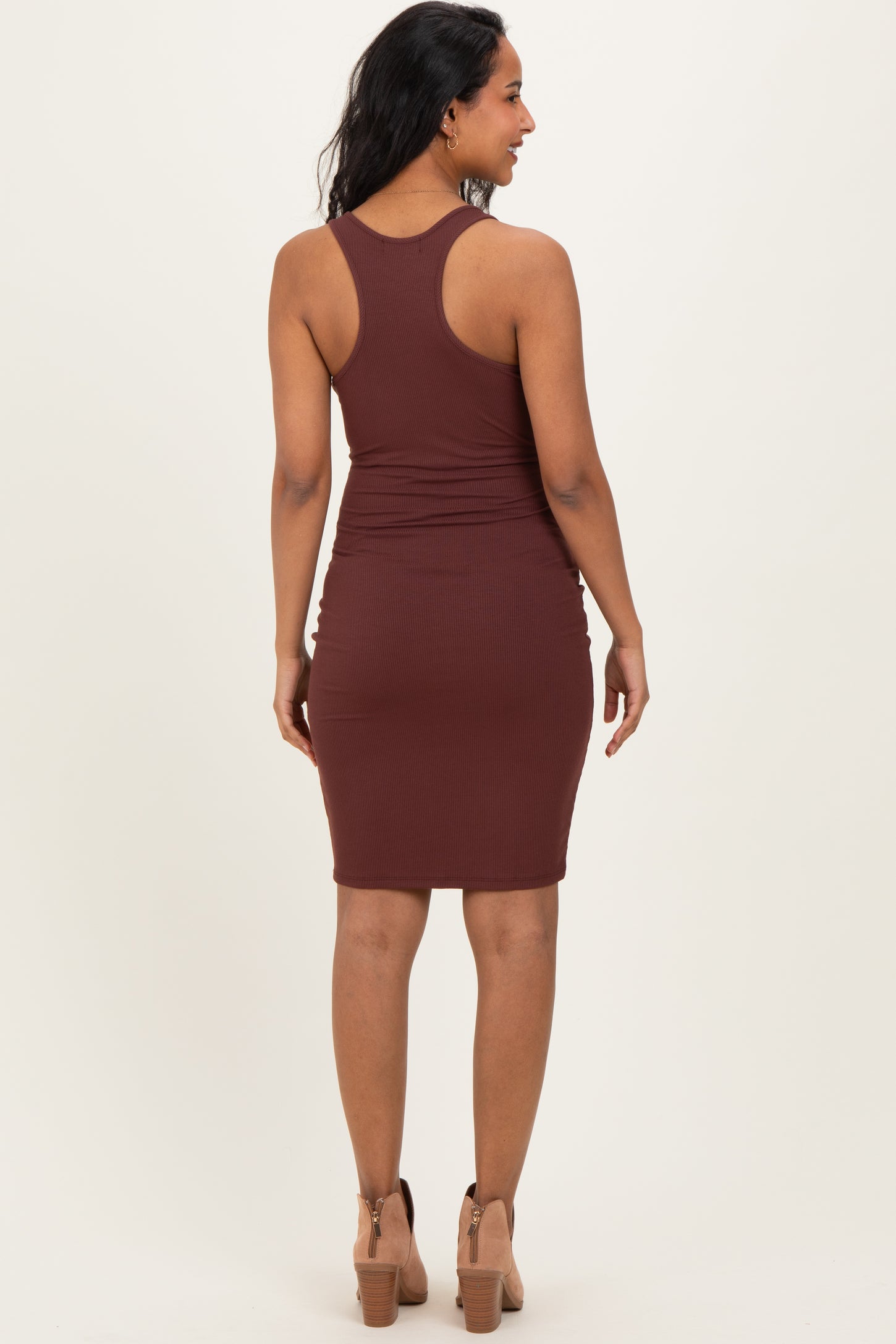 woman wearing a brown ribbed maternity dress with a fitted silhouette and racerback design, showing a baby bump