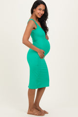 woman wearing a green fitted maternity dress showcasing her baby bump