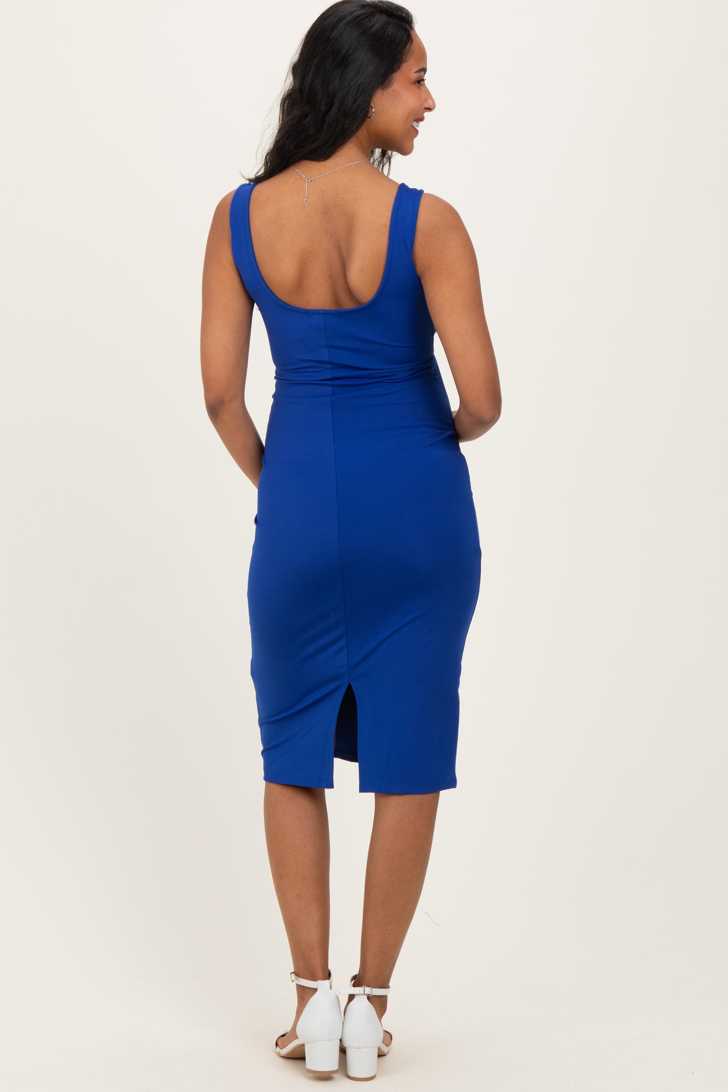 woman wearing a blue sleeveless maternity dress with a scoop back and a slit at the hem
