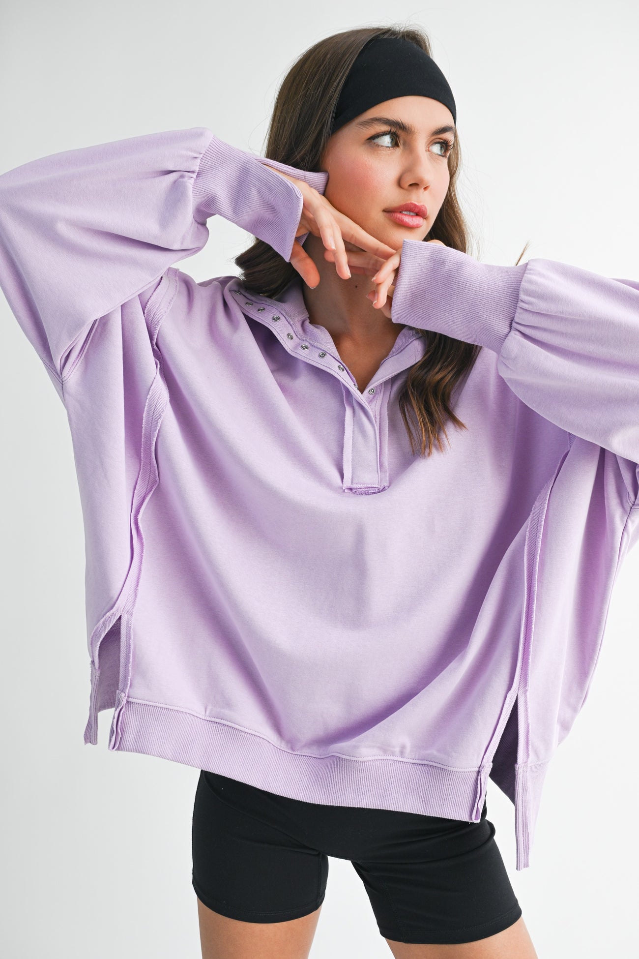 woman wearing a light purple oversized pullover sweatshirt with a henley collar and long sleeves