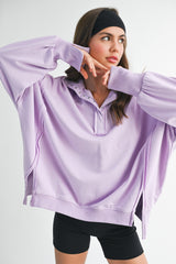 woman wearing a light purple oversized pullover sweatshirt with a henley collar and long sleeves