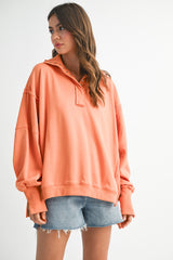 woman wearing a loose-fitting peach long sleeve pullover with a collar and paired with denim shorts