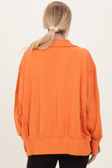 woman wearing an oversized orange sweatshirt with a collar, viewed from the back