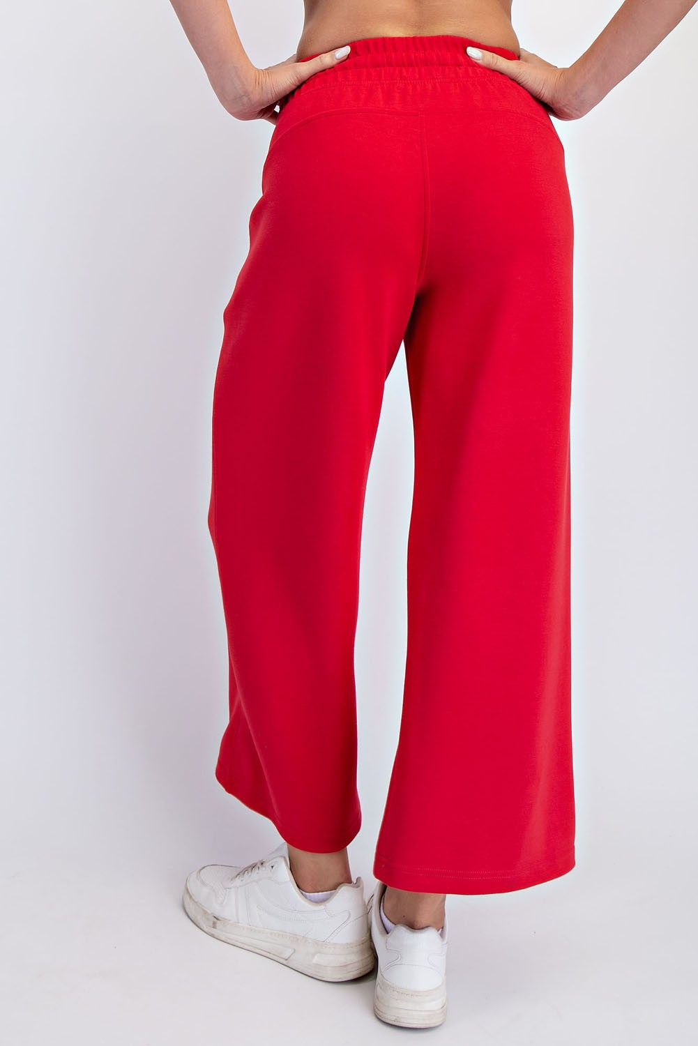 woman wearing red wide-leg sweatpants, seen from the back, paired with white sneakers