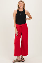 woman wearing a black sleeveless top and red wide-leg maternity pants with a drawstring waist