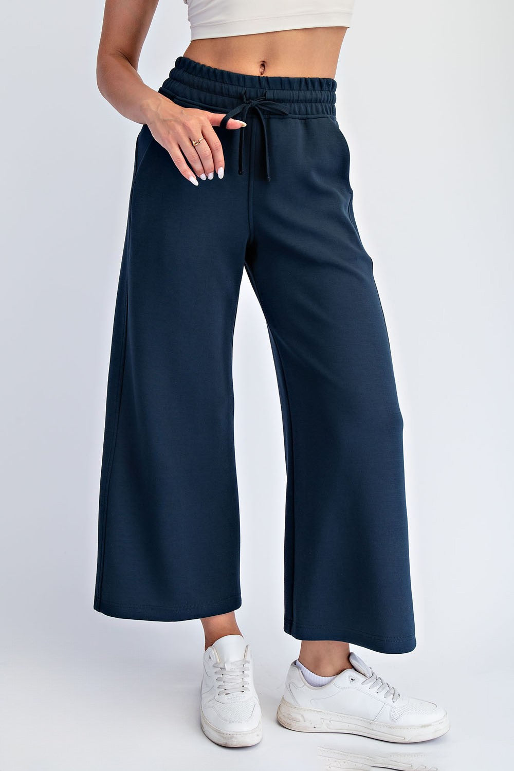 woman wearing navy blue wide-leg sweatpants with an elastic waistband and drawstring, paired with white sneakers
