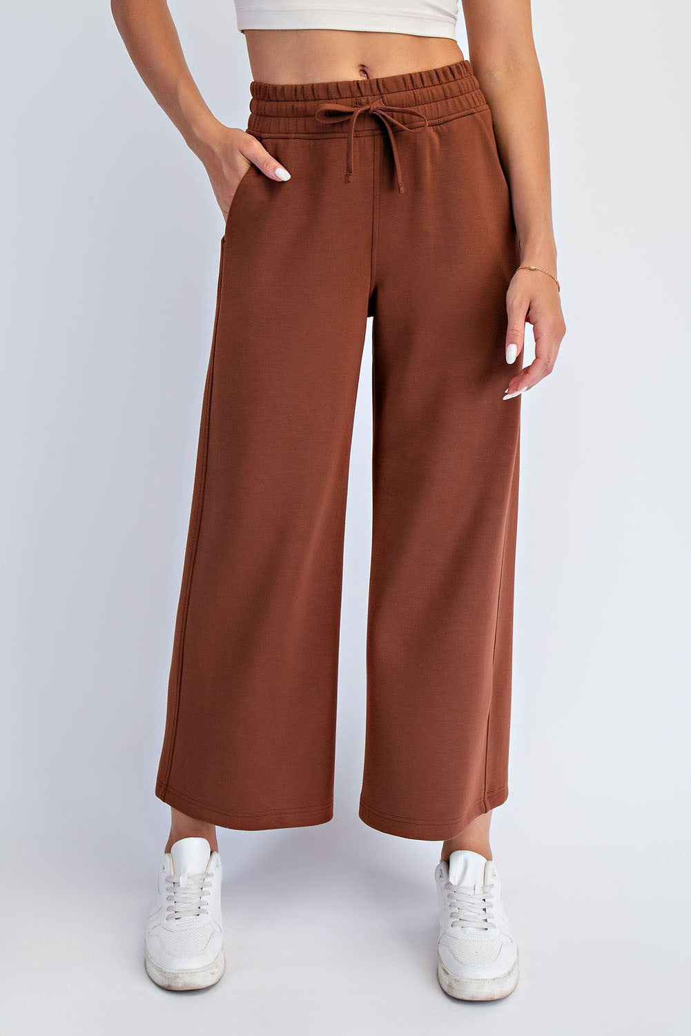 woman wearing brown wide-leg sweatpants with an elastic waistband and pockets, paired with white sneakers