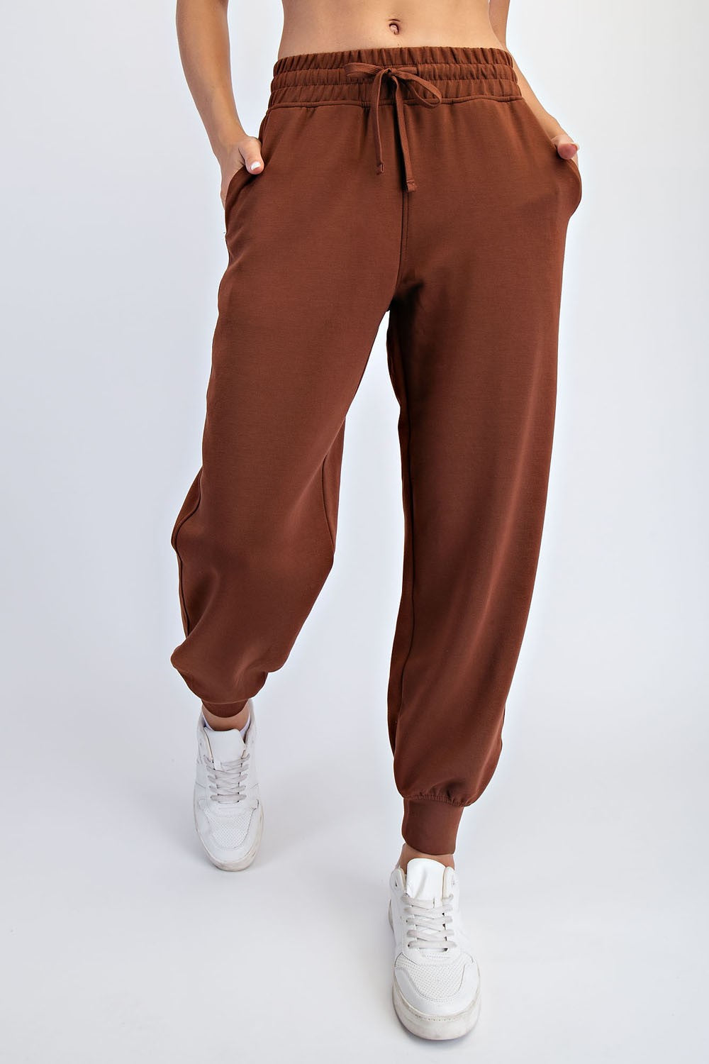 woman wearing brown jogger pants with an elastic waistband and pockets, styled with white sneakers