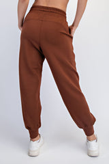 woman wearing brown jogger pants with elastic waistband and cuffs, seen from the back