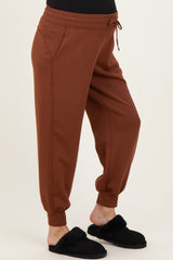 maternity wear rust colored joggers with side pockets and elastic cuffs, model wearing black slippers