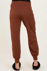 woman wearing brown maternity jogger pants with elastic ankle cuffs, viewed from the back