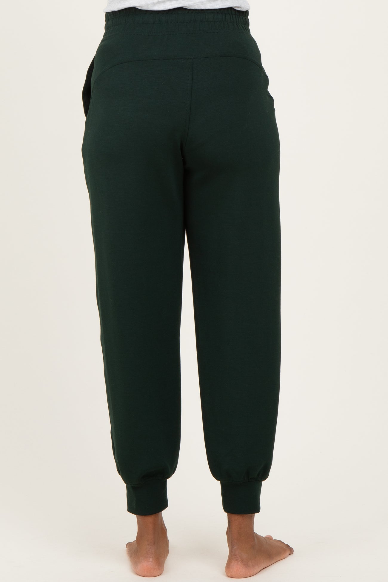 woman wearing dark green maternity jogger pants viewed from the back