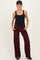 woman wearing a black maternity bodysuit and maroon wide-leg pants with pockets and a baseball cap