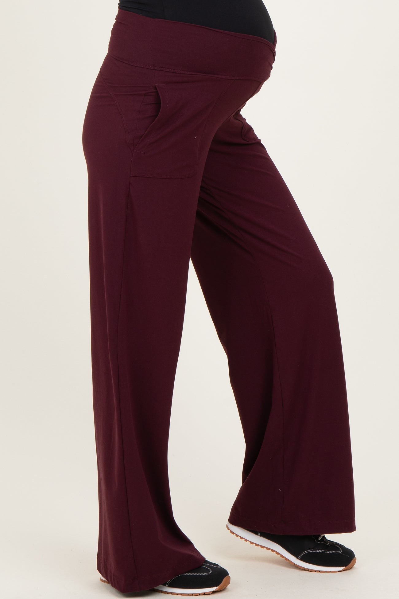 maternity wear in deep burgundy wide leg pants with side pockets, designed for comfort with a visible baby bump