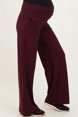 maternity wear in deep burgundy wide leg pants with side pockets, designed for comfort with a visible baby bump