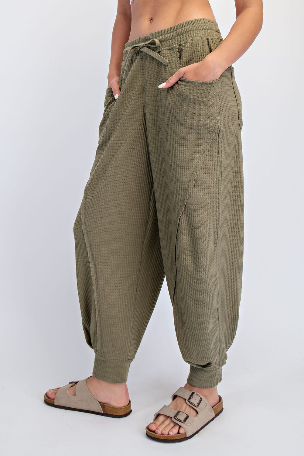 woman wearing olive green cropped harem pants with drawstring and side pockets