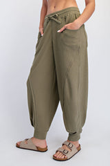 woman wearing olive green cropped harem pants with drawstring and side pockets