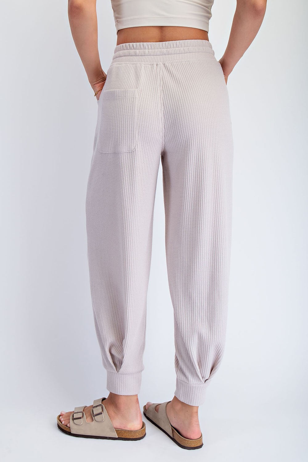 woman wearing light beige ribbed jogger pants with a tapered leg and back pocket, viewed from the back