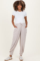 woman wearing a white short sleeve tee and beige maternity jogger pants with pockets, smiling and standing casually
