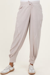 woman wearing light pink maternity joggers with side pockets and elastic cuffs, styled with white sneakers