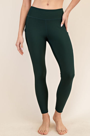 woman wearing dark green ribbed high-waisted leggings with side pockets