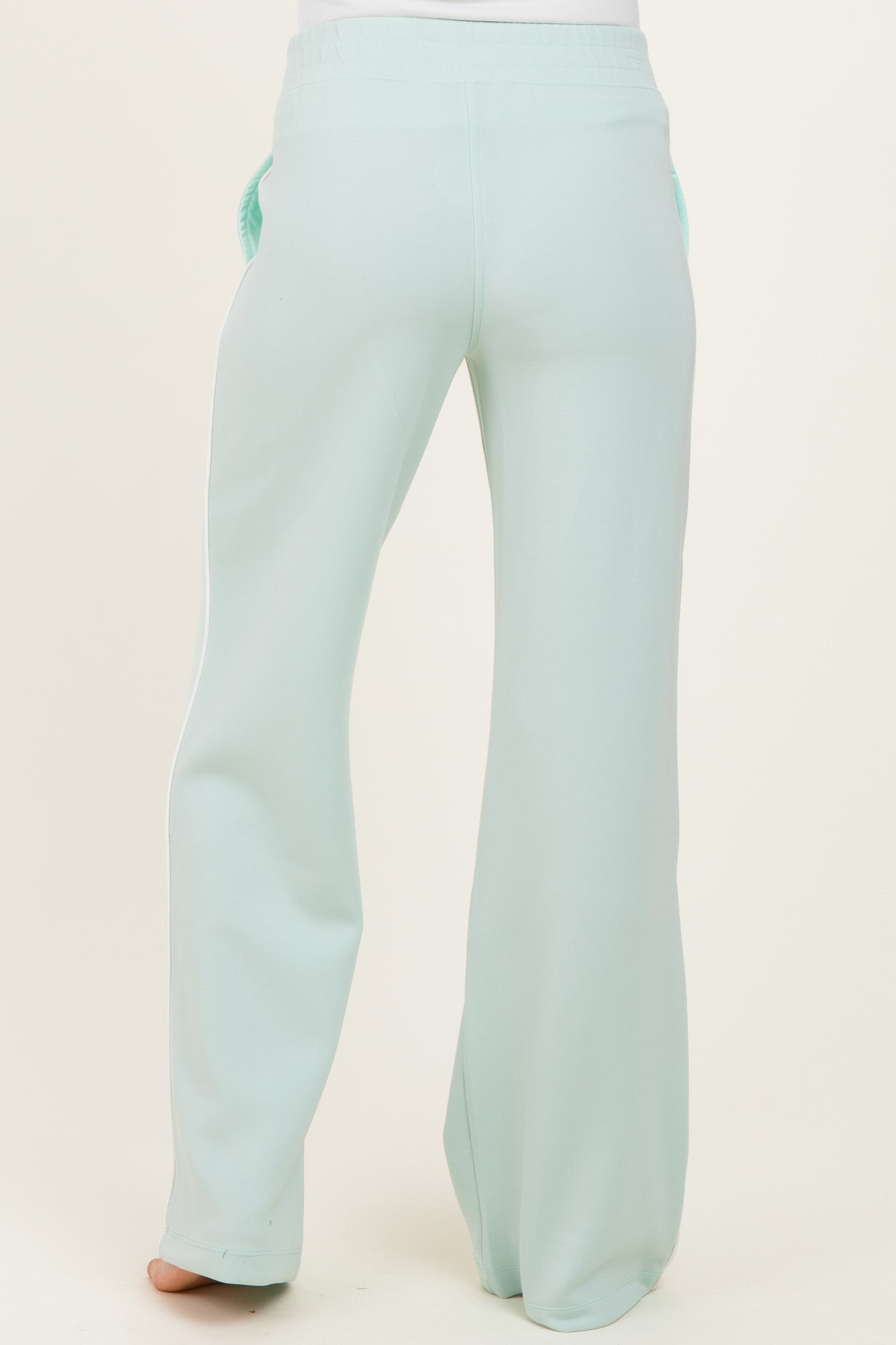 maternity wear in mint green, featuring wide-leg pants with a relaxed fit and side pockets, worn by a model from the back