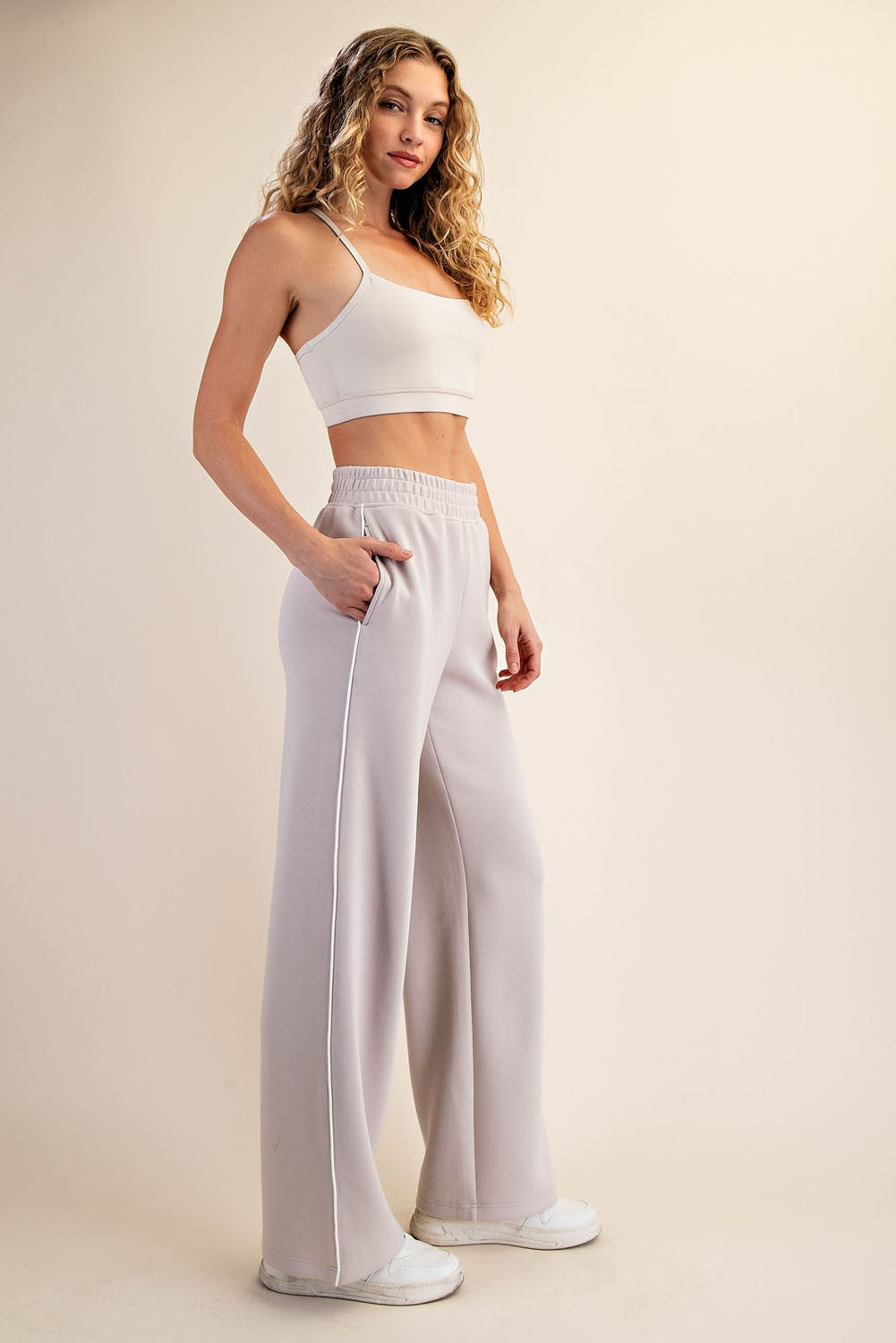 woman wearing a light grey crop top and matching wide-leg sweatpants with side pockets