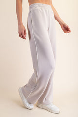 woman wearing light gray wide-leg sweatpants with side pockets and a drawstring waist, paired with white sneakers