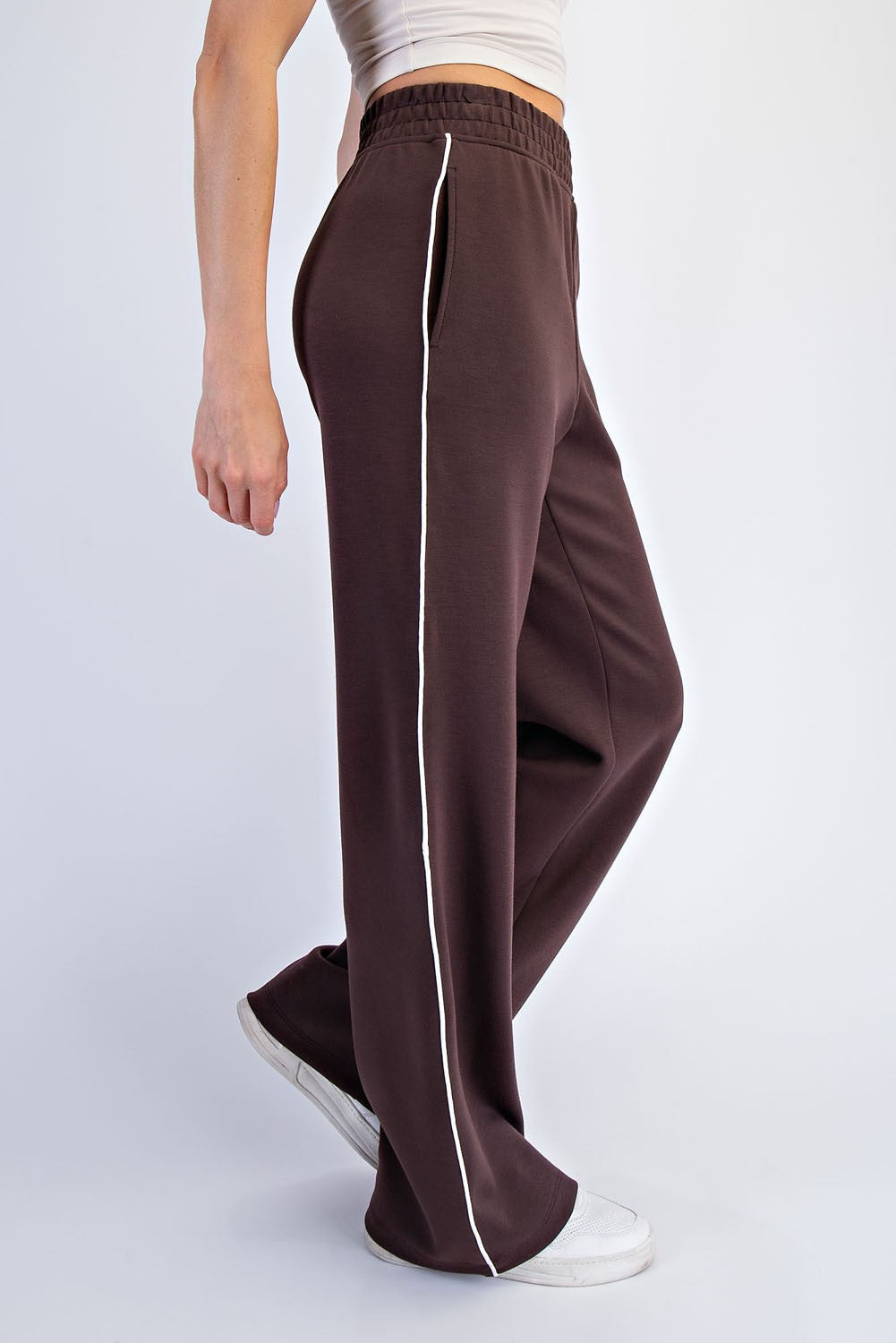woman wearing brown wide-leg sweatpants with white side stripes and an elastic waistband