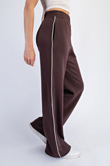woman wearing brown wide-leg sweatpants with white side stripes and an elastic waistband