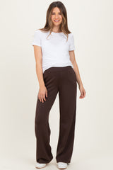 woman wearing a white short sleeve top and brown maternity wide-leg pants, posing with a relaxed smile